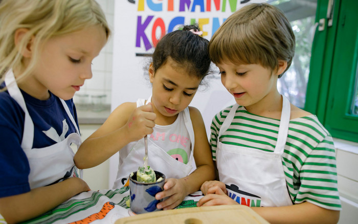 Kinder rühren gemeinsam eine Kräuterbutter an im Rahmen einer Ich kann kochen!-Kochaktion.